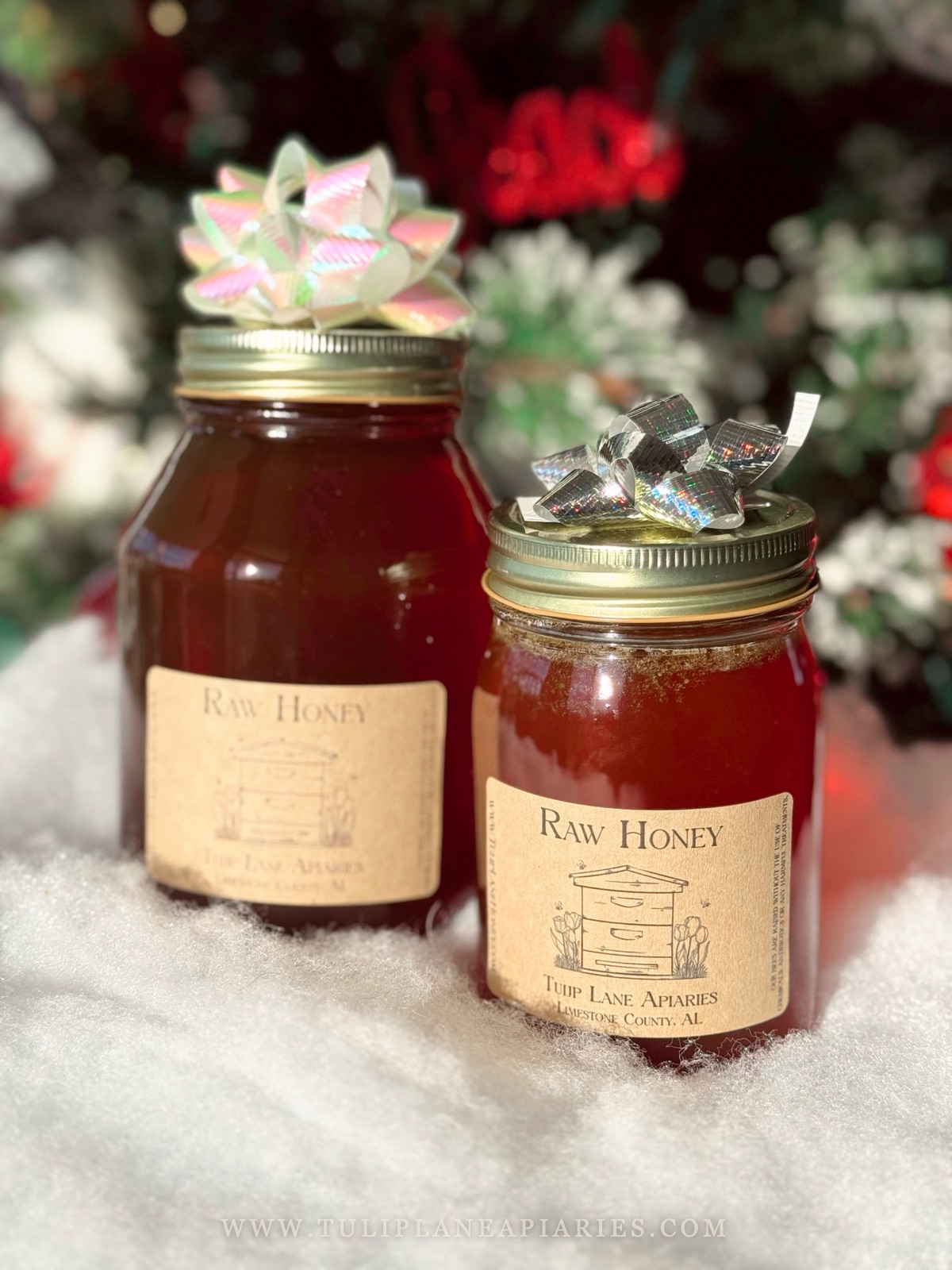 Two jars of Tulip Lane raw honey topped with gift bows